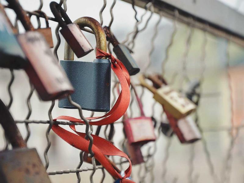 Cadenas avec ruban rouge attaché à une grille.